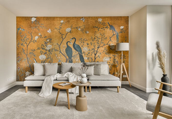 Goldenes Wandgemälde mit Vögeln und Blumen in einem modern eingerichteten Wohnzimmer mit hellem Sofa, Raumgestaltung nach Feng Shui